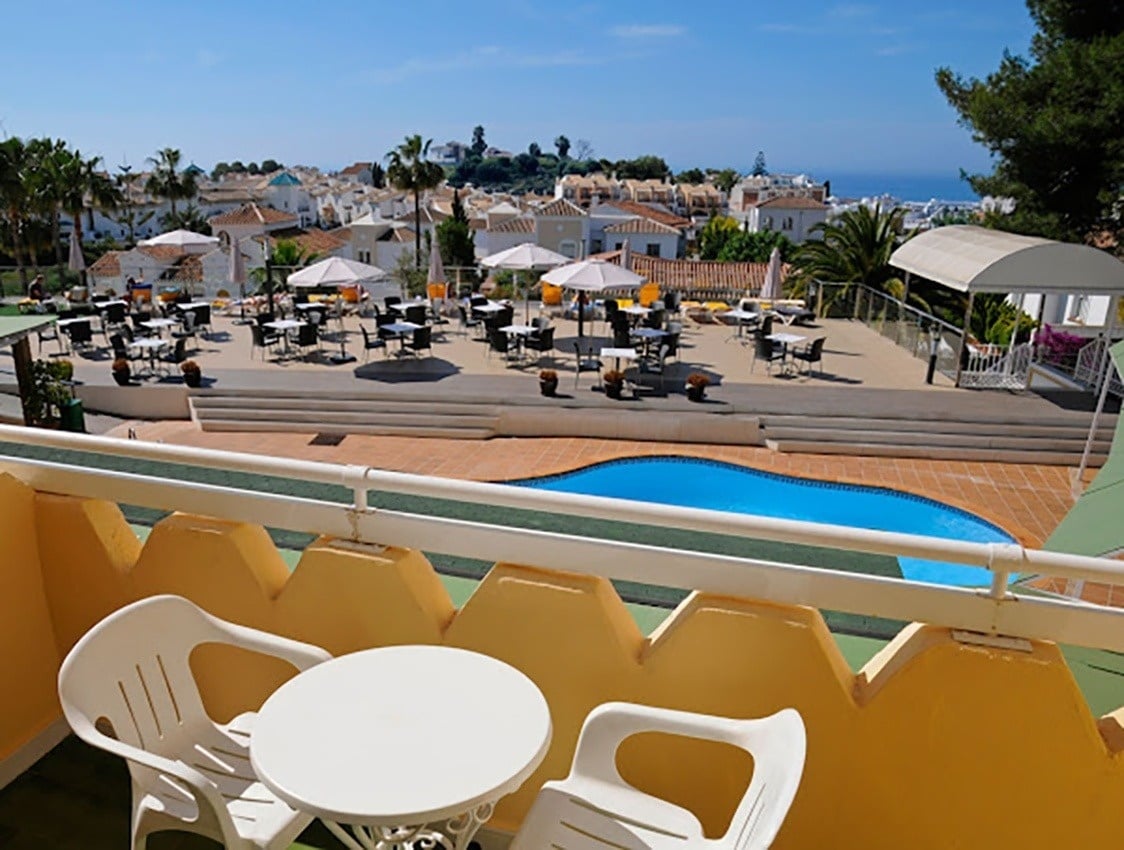 una mesa y sillas en un balcón con vistas a una piscina