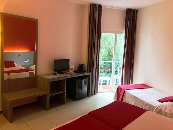 una habitación de hotel con dos camas , una mesa , una televisión y una puerta corrediza .