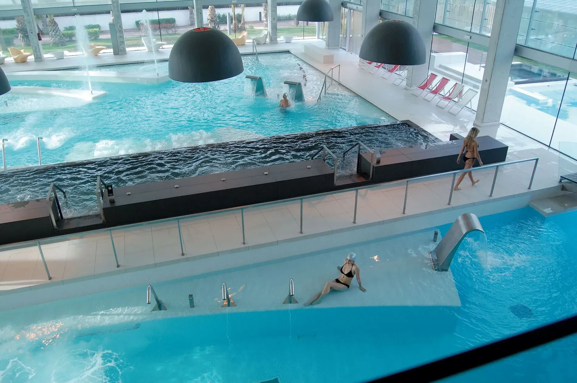 Relájate en la piscina termal de ESTIVAL: Park Silmar con cascadas y tumbonas.