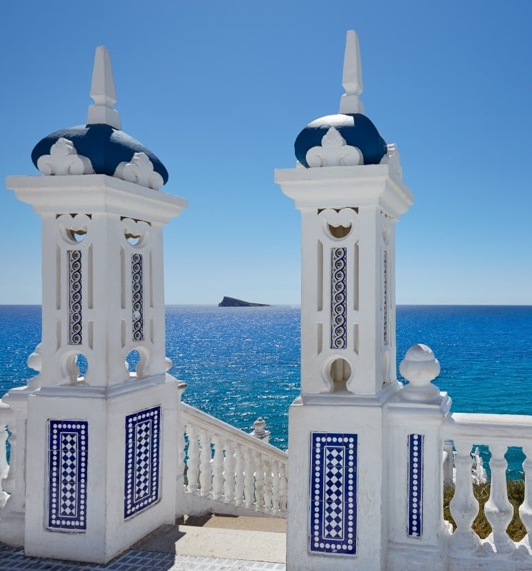 dos columnas blancas con azulejos azules están frente al océano