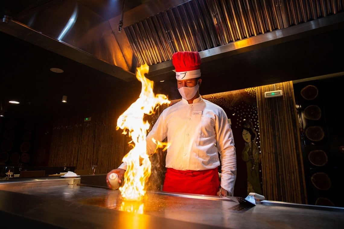 a chef wearing a mask and a red hat is cooking