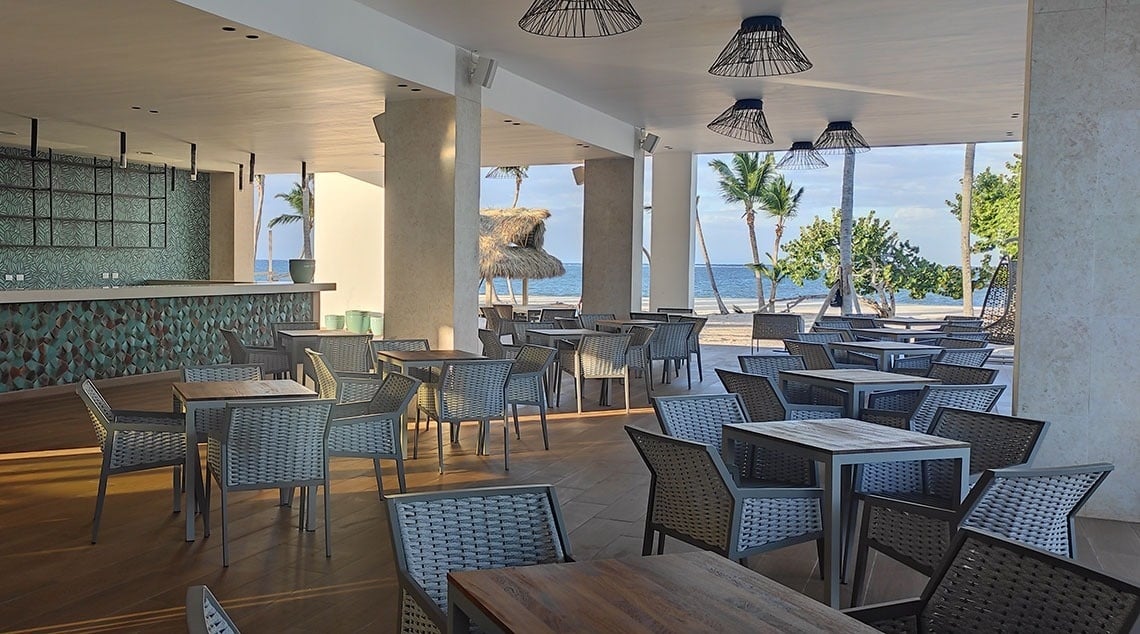 a restaurant with tables and chairs with a view of the ocean
