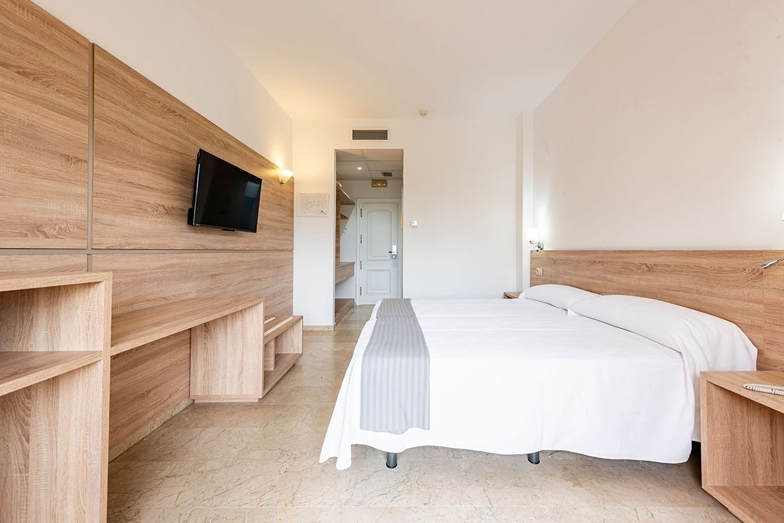 a hotel room with two beds and a flat screen tv