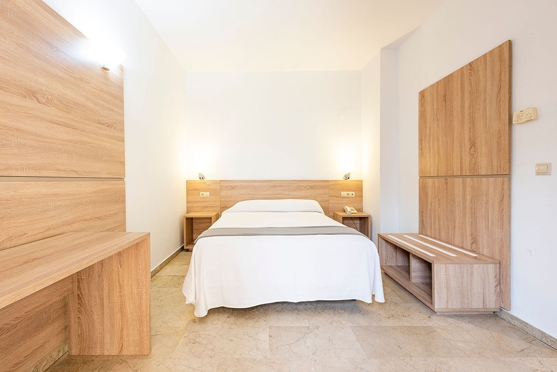 una habitación con una cama y dos mesitas de noche de madera