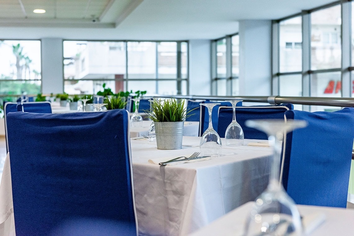 un restaurante con mesas y sillas azules y copas de vino