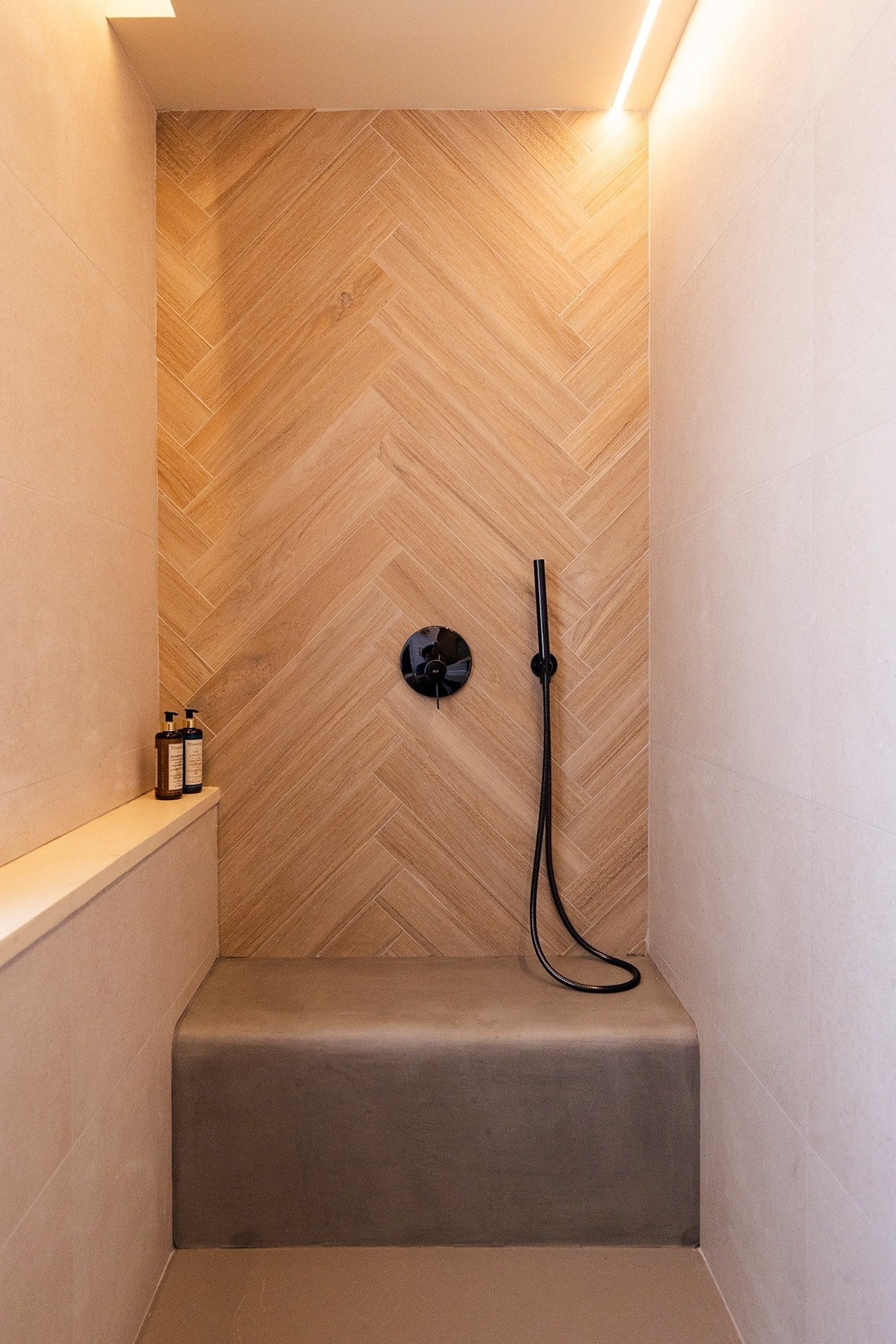 a shower with a wooden wall and a black shower head