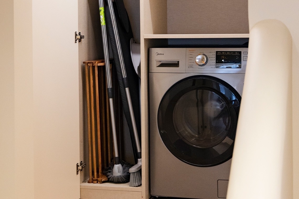 a silver midea washing machine sits in a closet