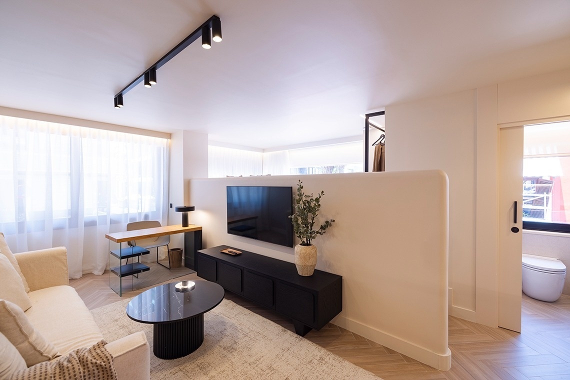 a living room with a couch a desk and a flat screen tv