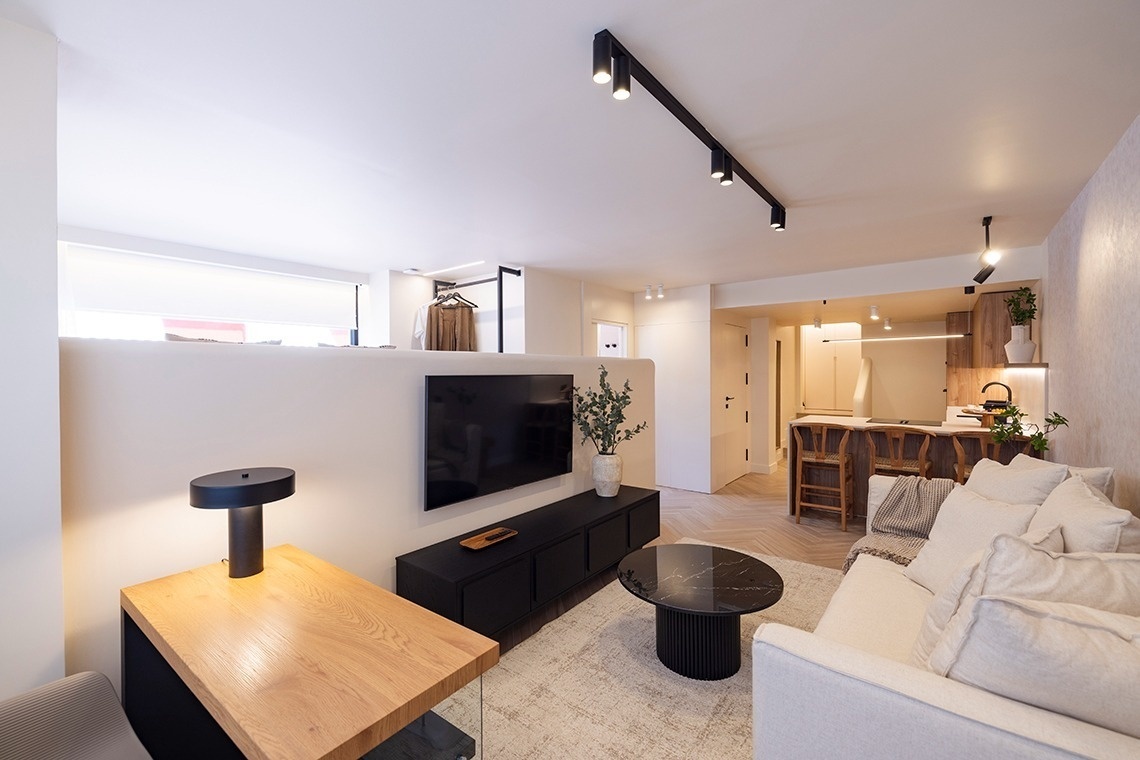 a living room with a couch a desk and a flat screen tv