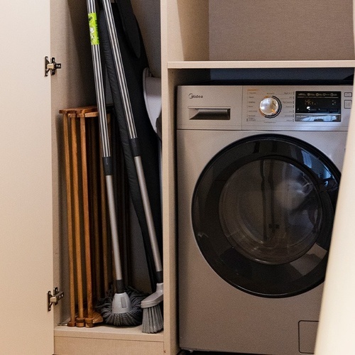 a silver midea washing machine sits in a closet