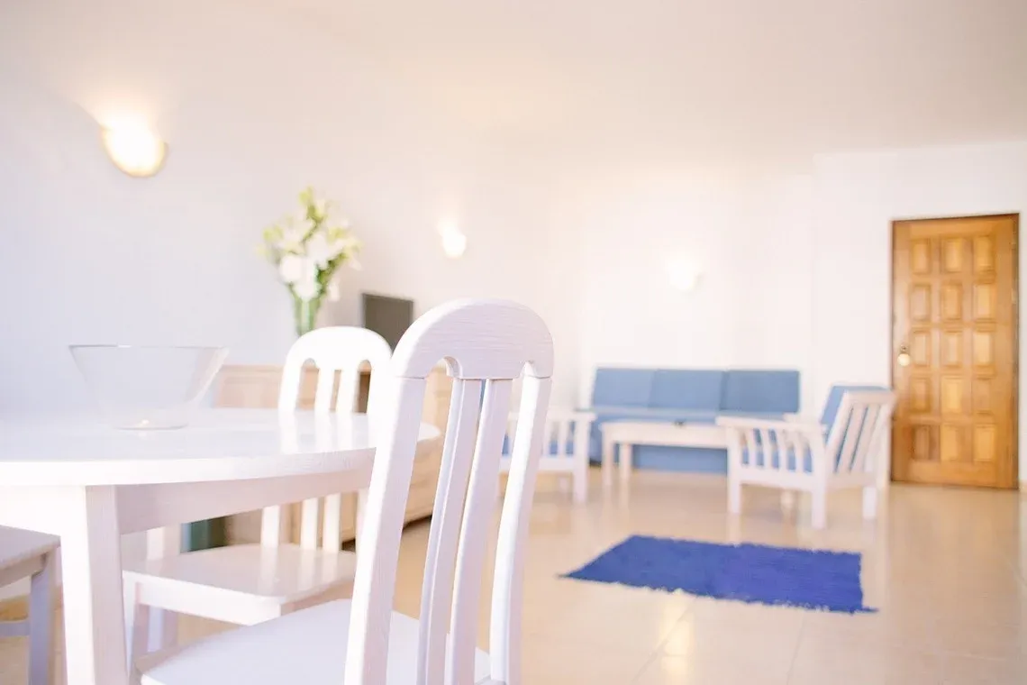 Comedor y sala de estar luminosos en Torralvor: Corporativa, con muebles blancos y sofá azul.