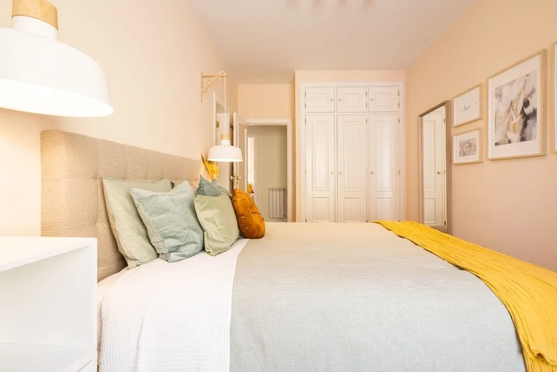 Twin beds in a hotel room, perfect for a solo traveler or friends, with colorful pillows and a reading lamp. Torralvor: Corporativa