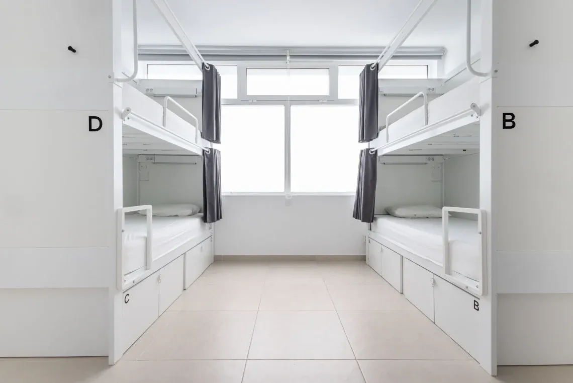Bright bedroom with white bedding, blue striped pillows, and mirrored wardrobe. Torralvor: Corporativa