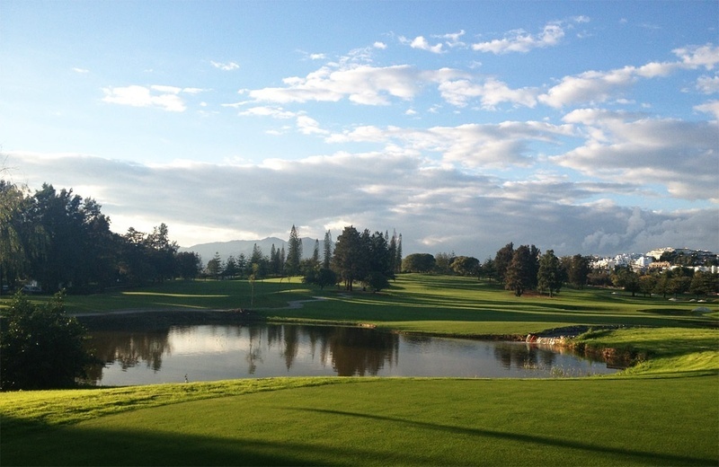 un grupo de golfistas están jugando en un campo de golf con una montaña en el fondo