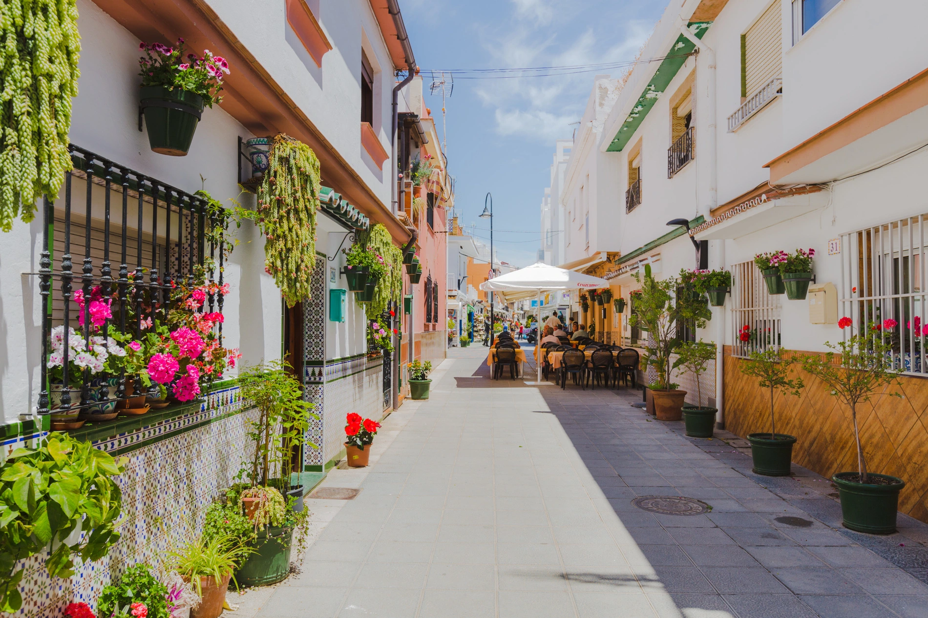 Charming street with potted plants and outdoor seating at a Things to do in Mijas, Málaga | Torrenueva Park | Official Web.