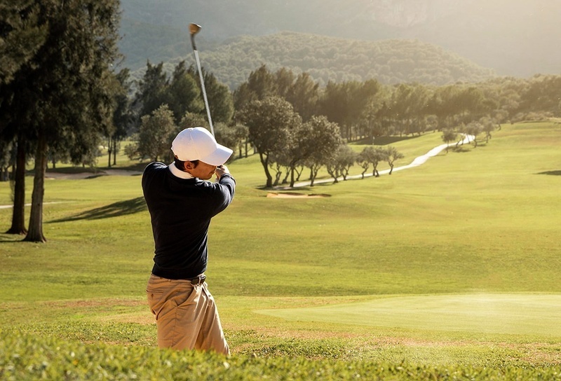 un grupo de golfistas están jugando en un campo de golf con una montaña en el fondo
