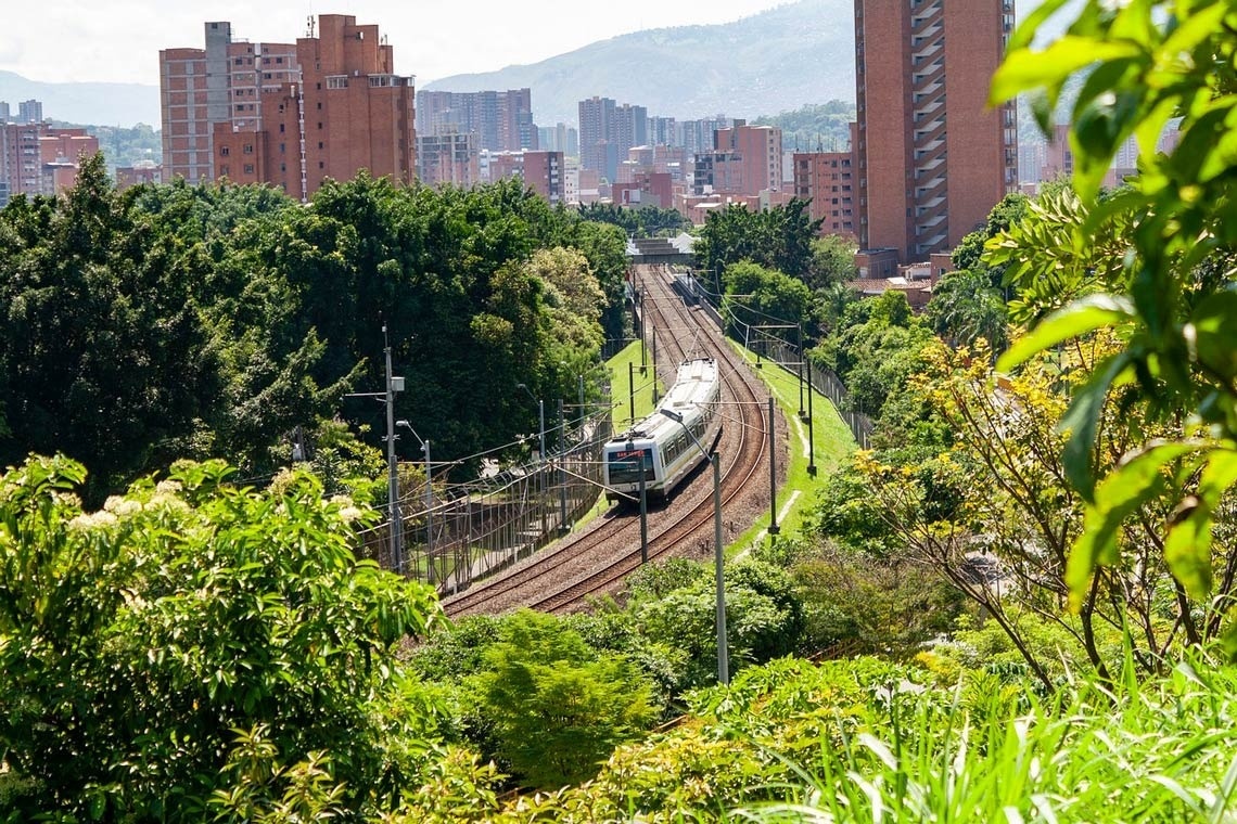 a train is going down the tracks with a city in the background