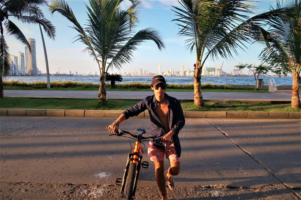 a man standing next to a bicycle with a city in the background