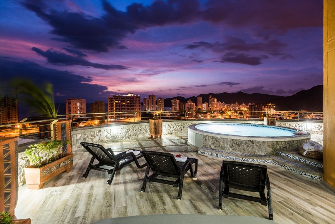 a hot tub on the roof of a building with a city in the background