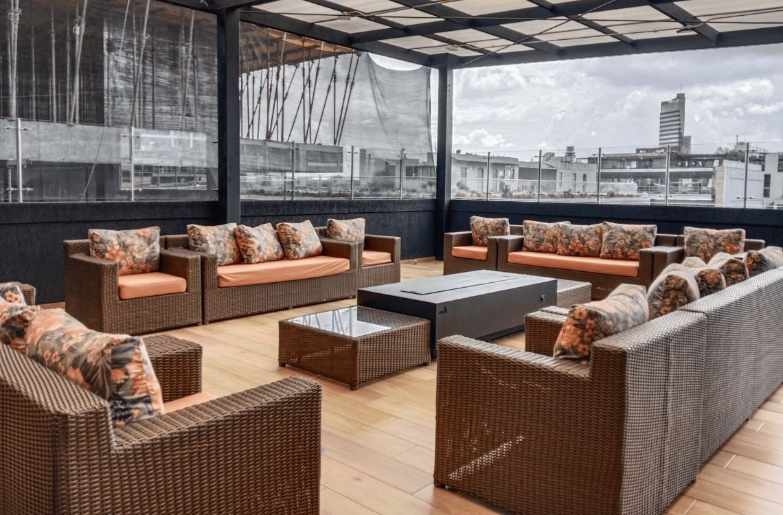 Luxurious rooftop lounge with woven furniture, ideal for corporate travelers.
