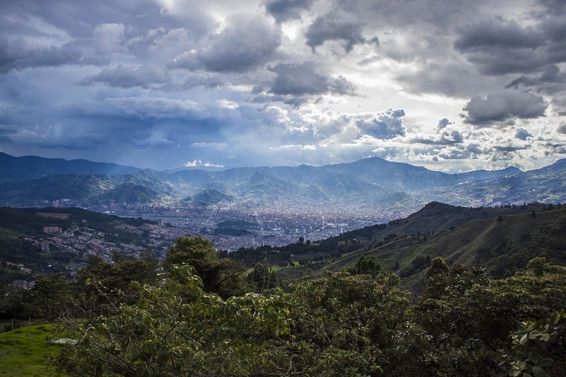 a view of a city surrounded by mountains on a cloudy day