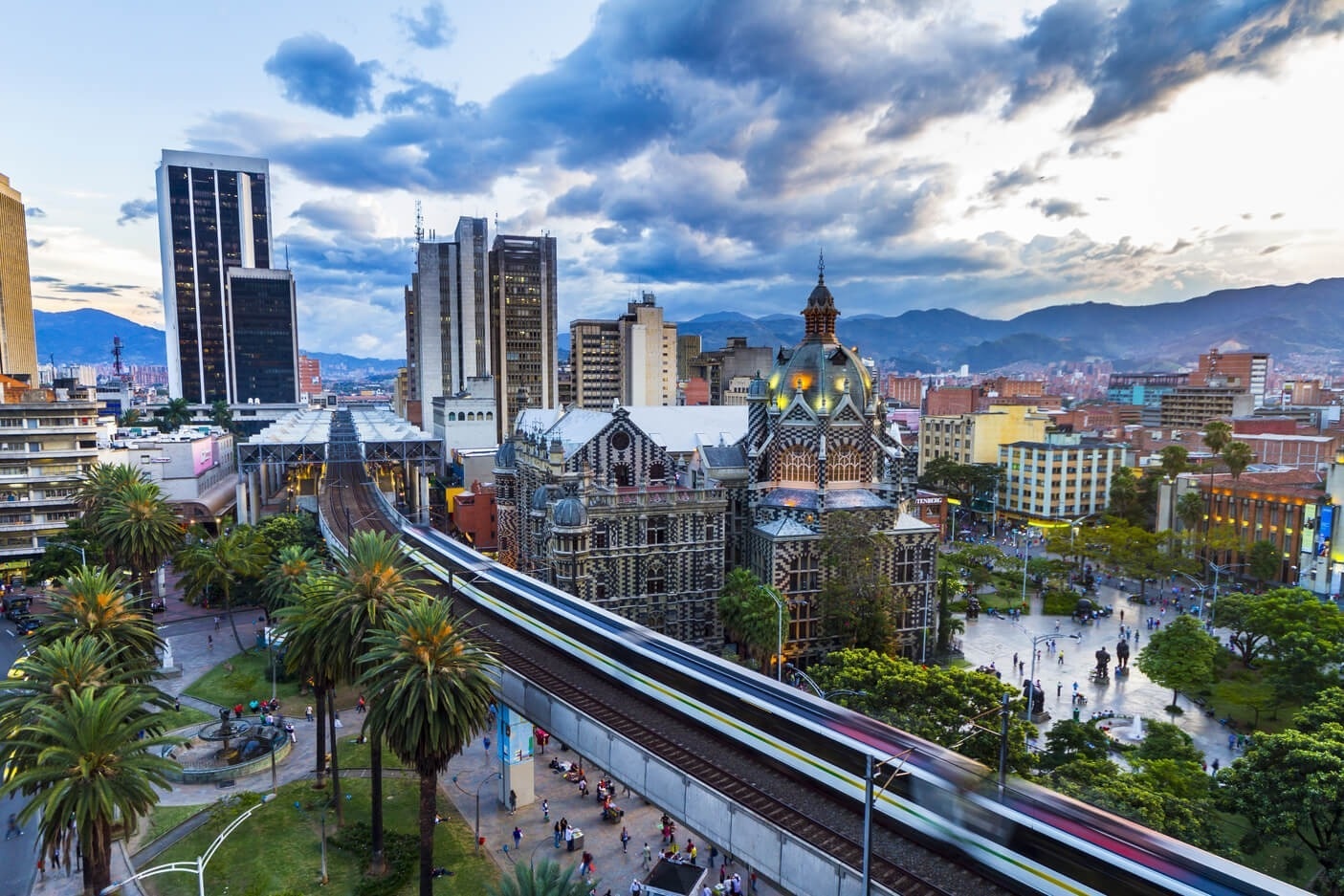 a train going through a city with mountains in the background