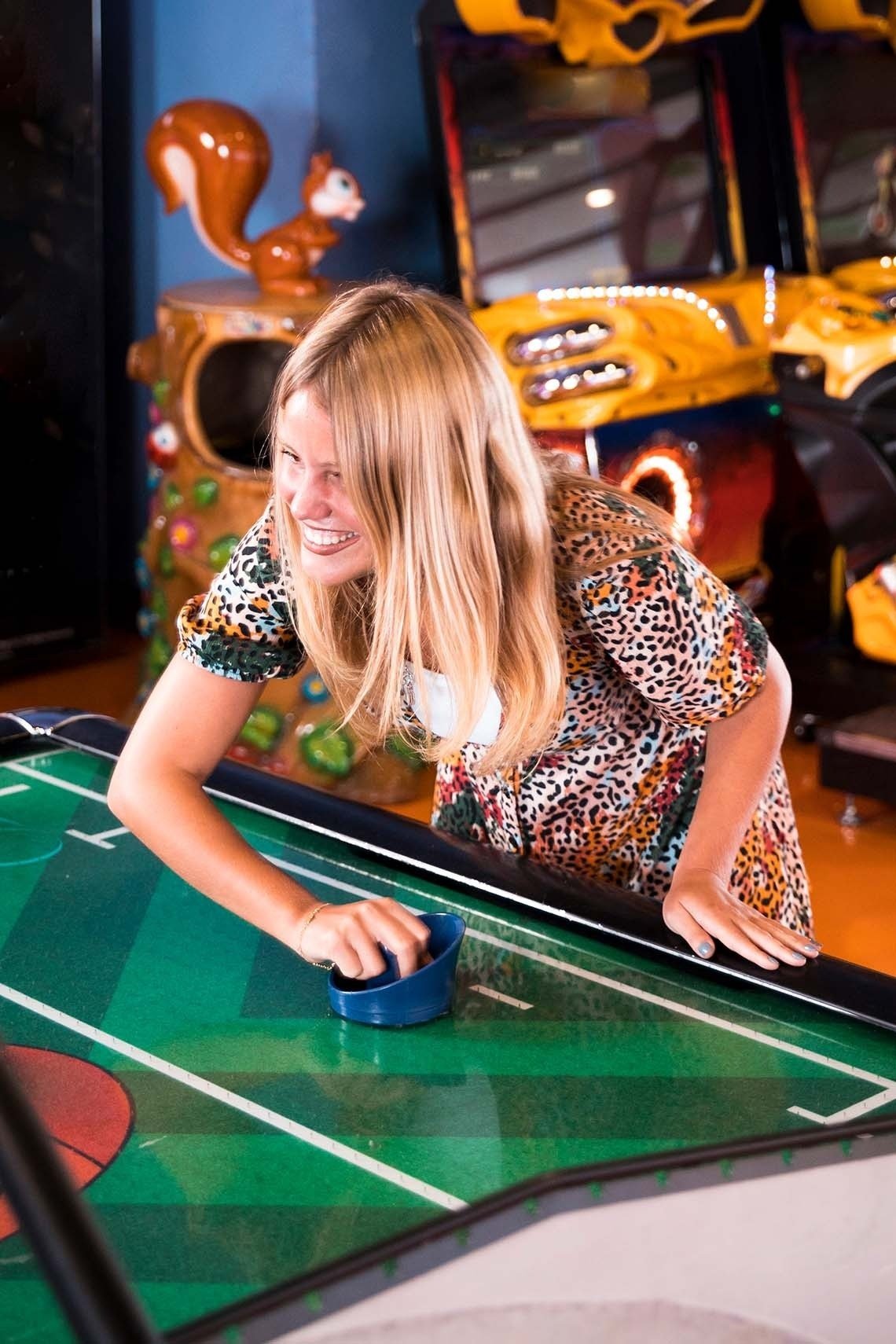 a woman is playing an air hockey game in an arcade