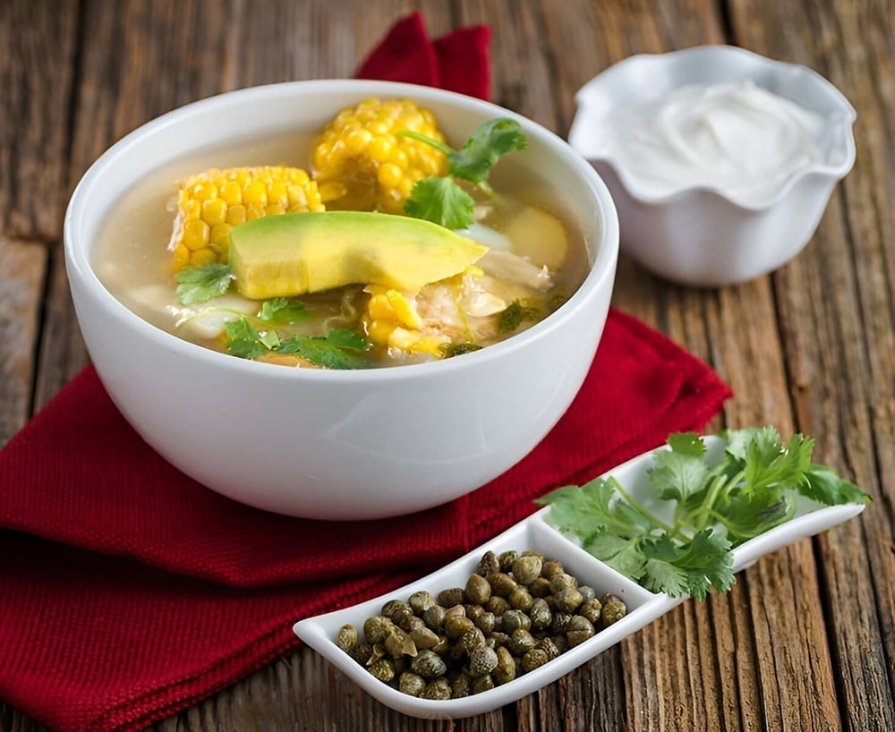 un tazón de sopa con maíz , aguacate y pollo está sobre una mesa de madera .