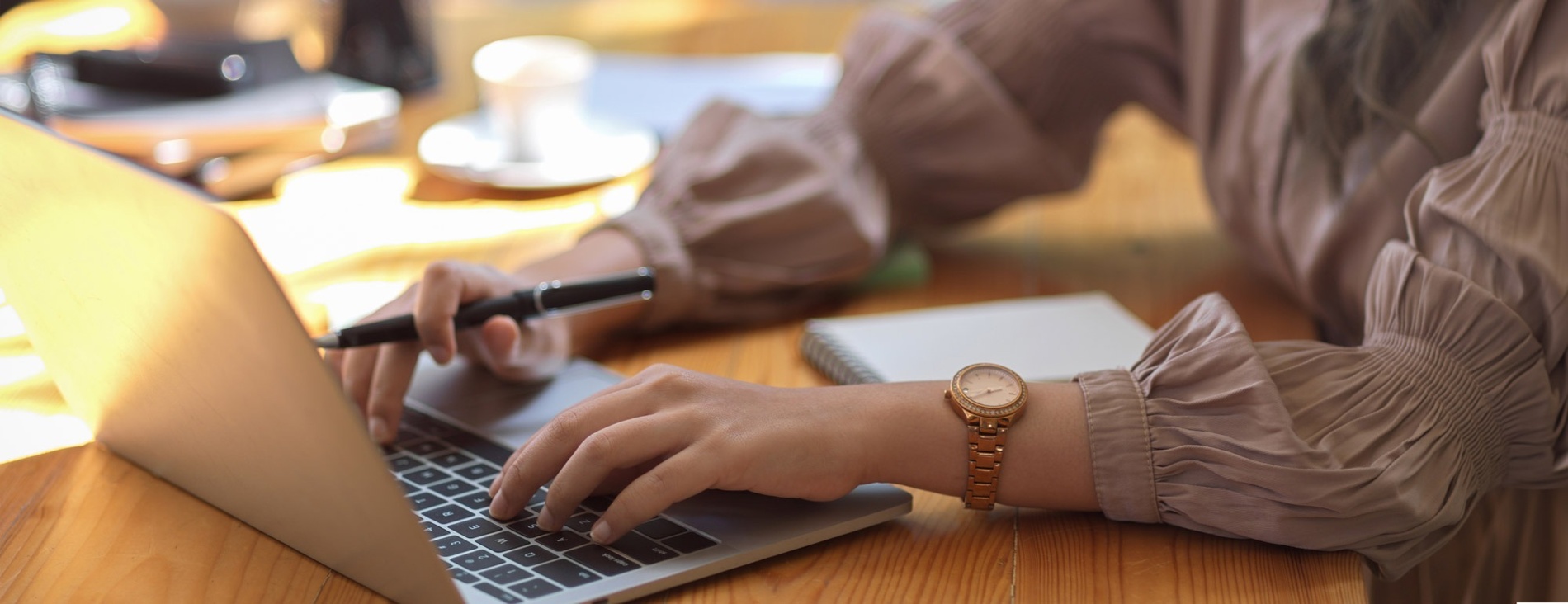 una mujer con un reloj en la muñeca está escribiendo en una computadora portátil