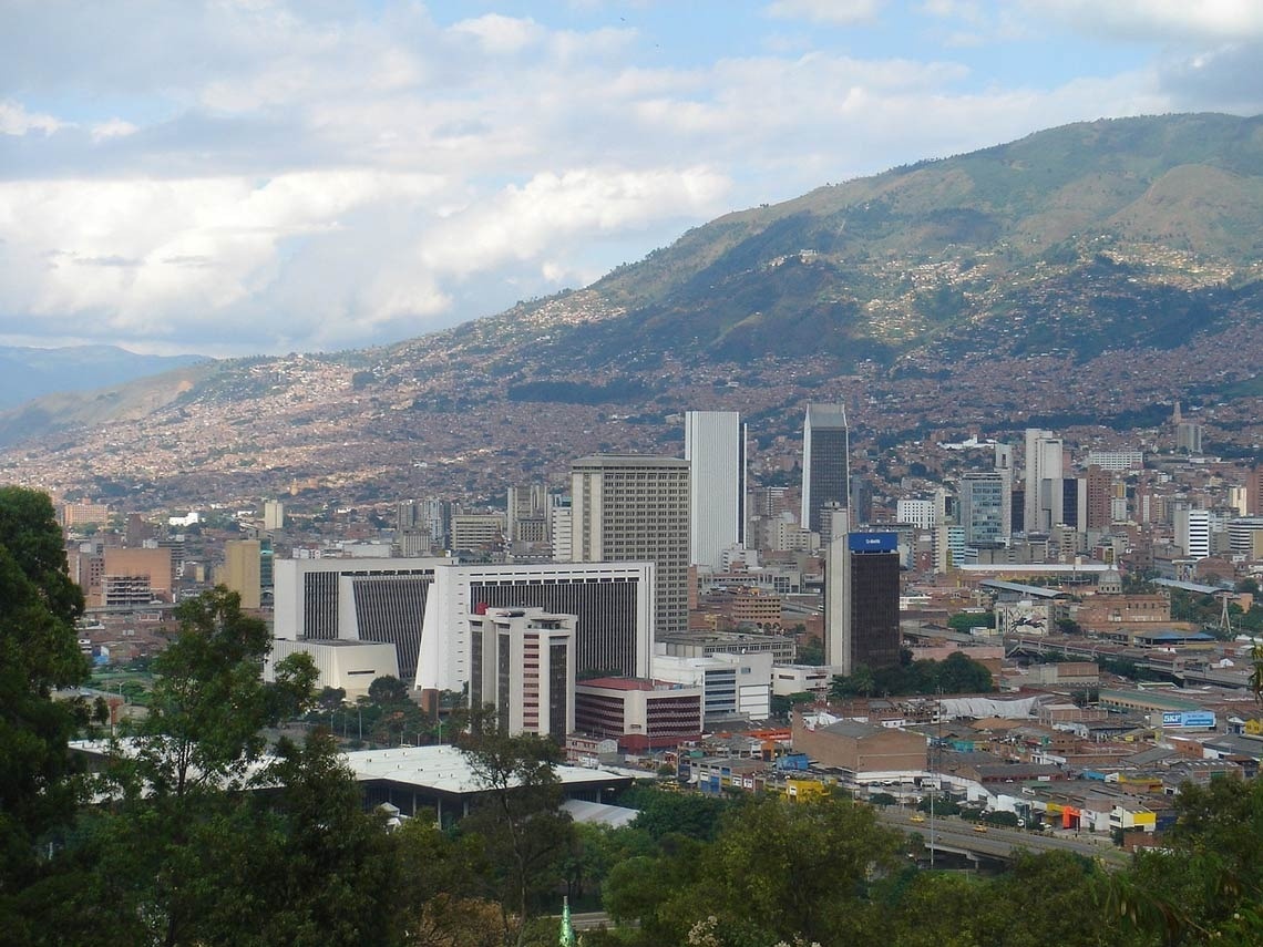 a city with mountains in the background and a building that says ' banco ' on it