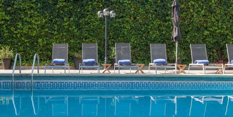 una piscina llena de sillas y sombrillas con toallas azules