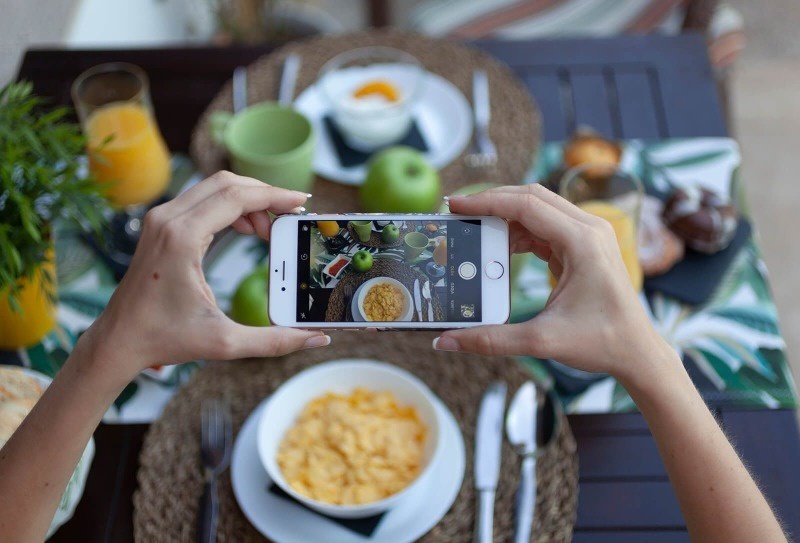 una persona está tomando una foto de un desayuno con un teléfono inteligente
