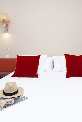 una cama blanca con almohadas rojas y una revista