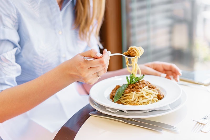 Sit at the table. Люди едят макароны вид сверху. Sportswoman eating pasta.