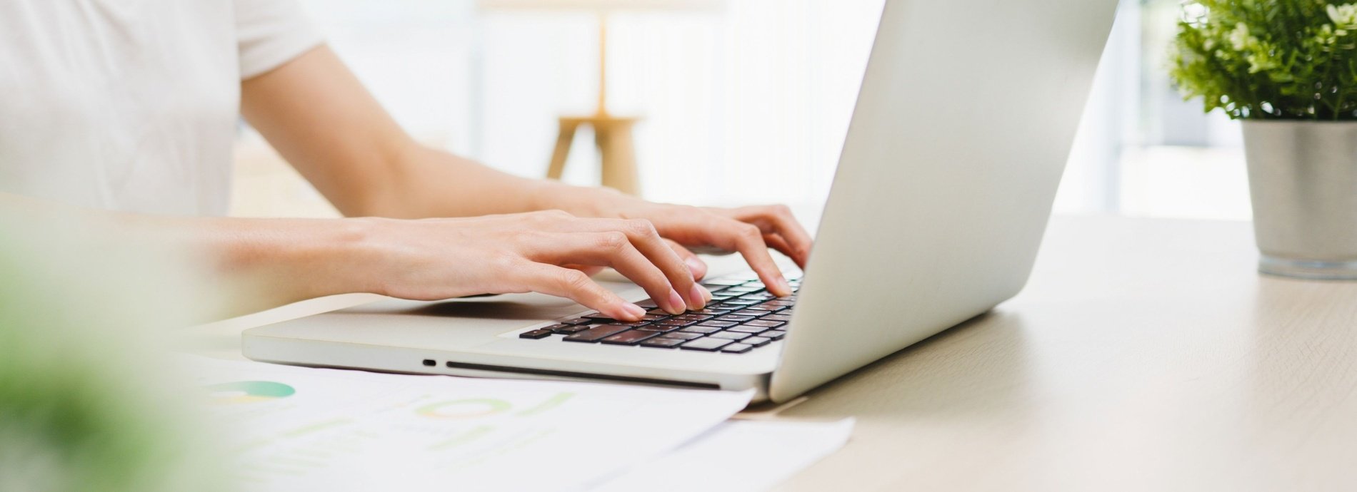 a woman is typing on a laptop next to a cup of coffee