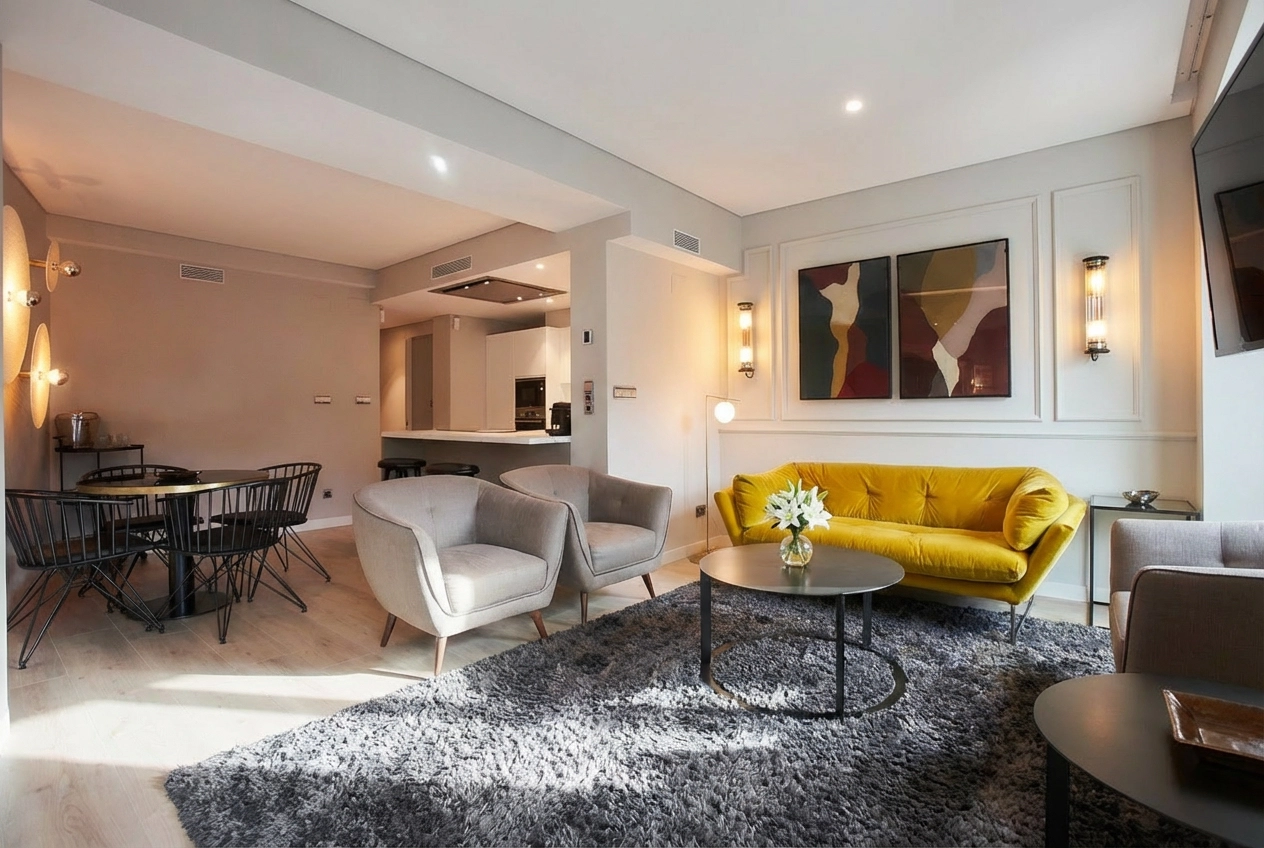 Una sala de estar con un sofá amarillo y dos sillas. U-Sense Madrid Santa Ana