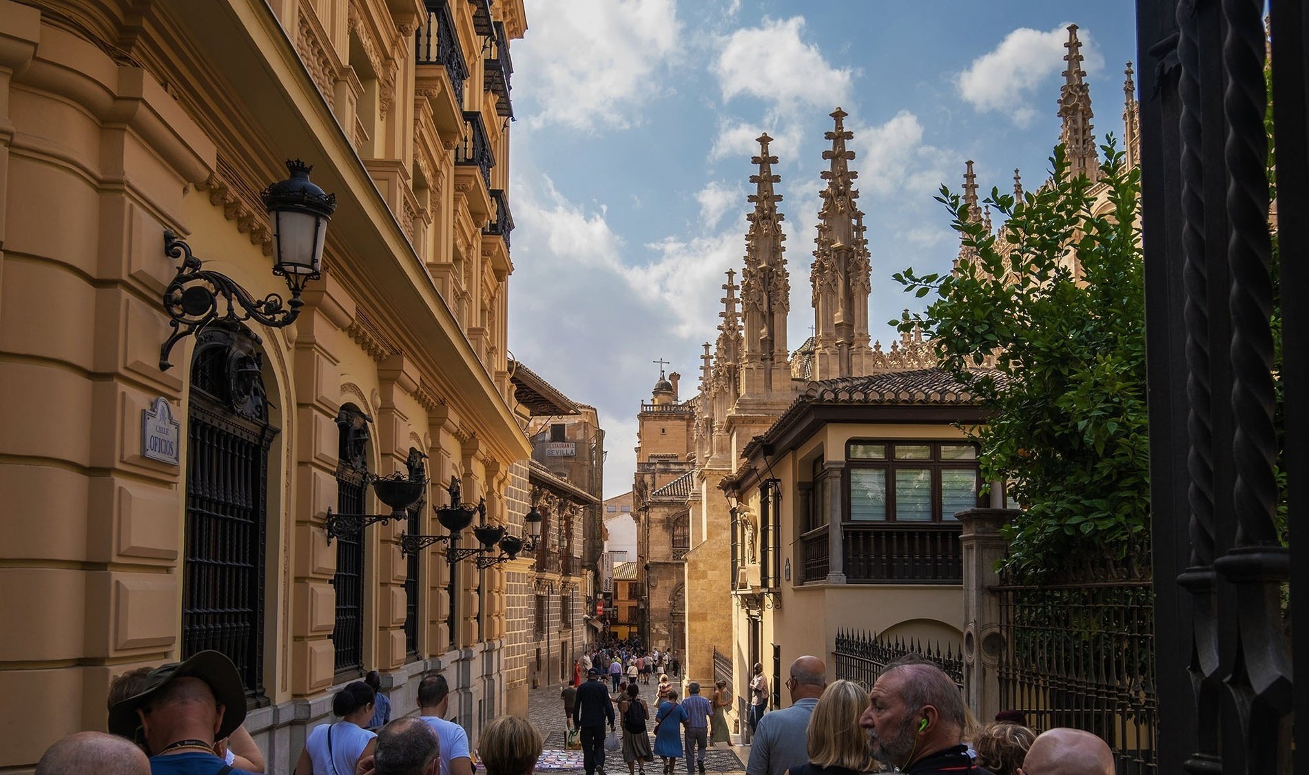 a group of people are walking down a narrow street in front of a building with a sign that says ' plaza '