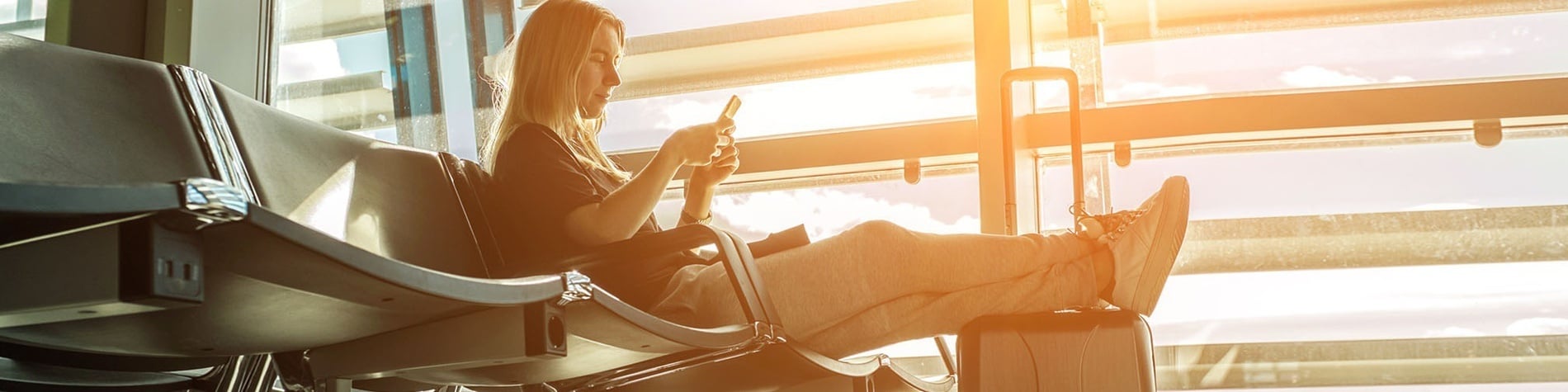 una mujer se sienta en una silla con las piernas cruzadas y mira su teléfono