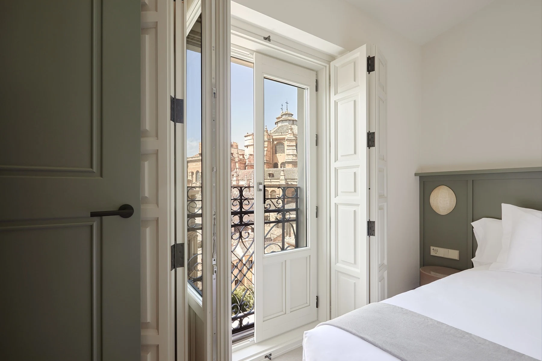 Vista de un apartamento moderno de planta abierta con sala de estar y comedor integrados, con un sofá beige y un sillón mariposa blanco. U-Sense
