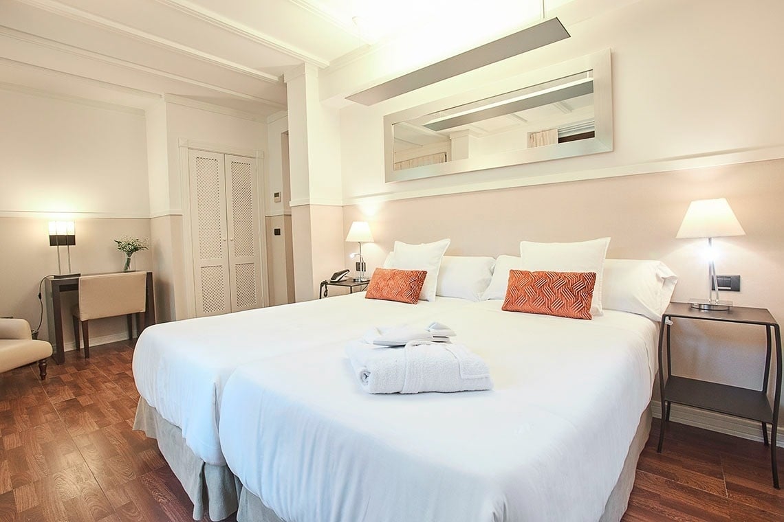 una habitación de hotel con una cama blanca y almohadas naranjas