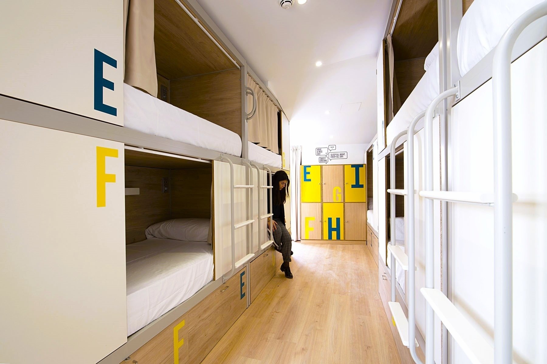 a woman is standing in a hallway with lockers that have the letters a c g and f on them