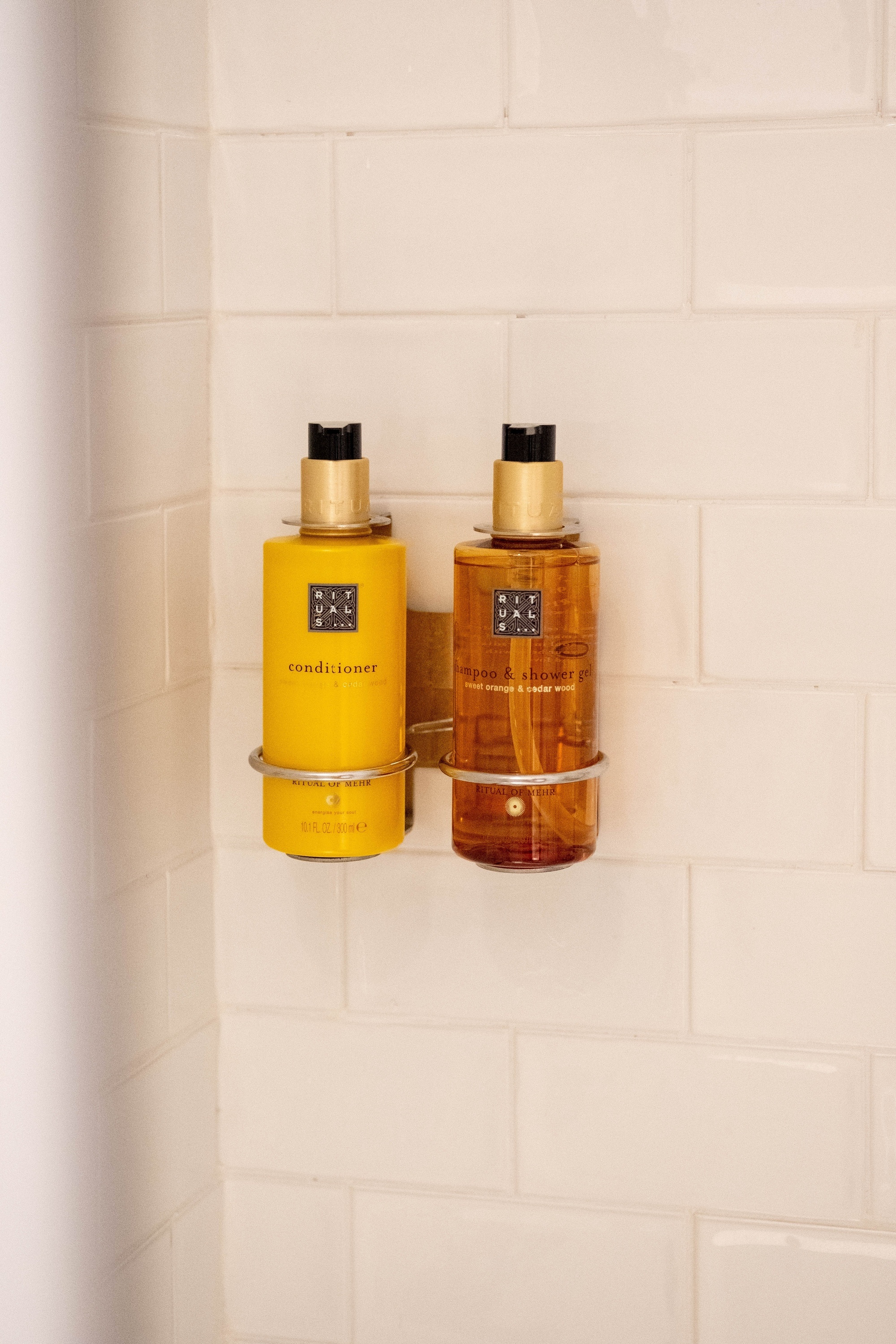 una botella de acondicionador y una botella de jabón están colgando en una pared de ladrillos