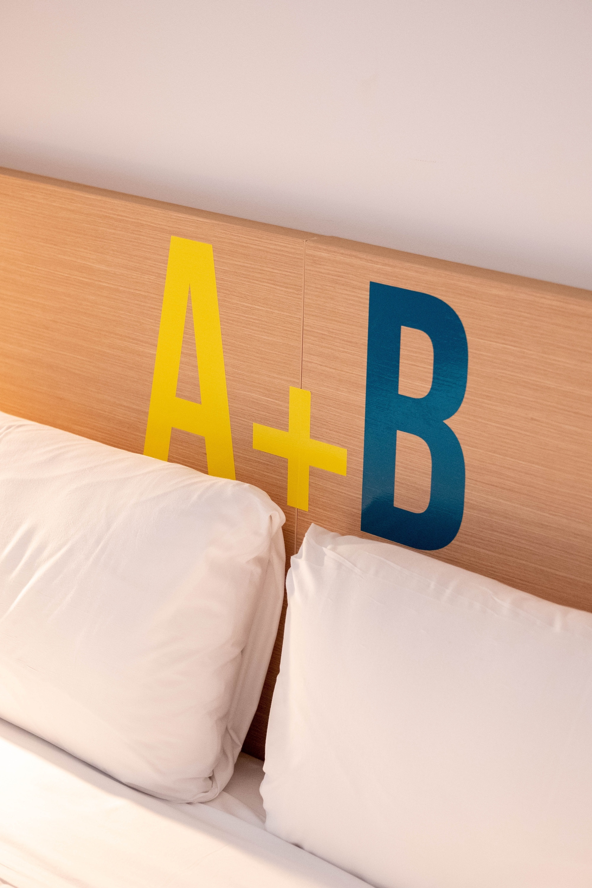 una cama con una cabecera de madera con las letras a + b pintadas en amarillo y azul
