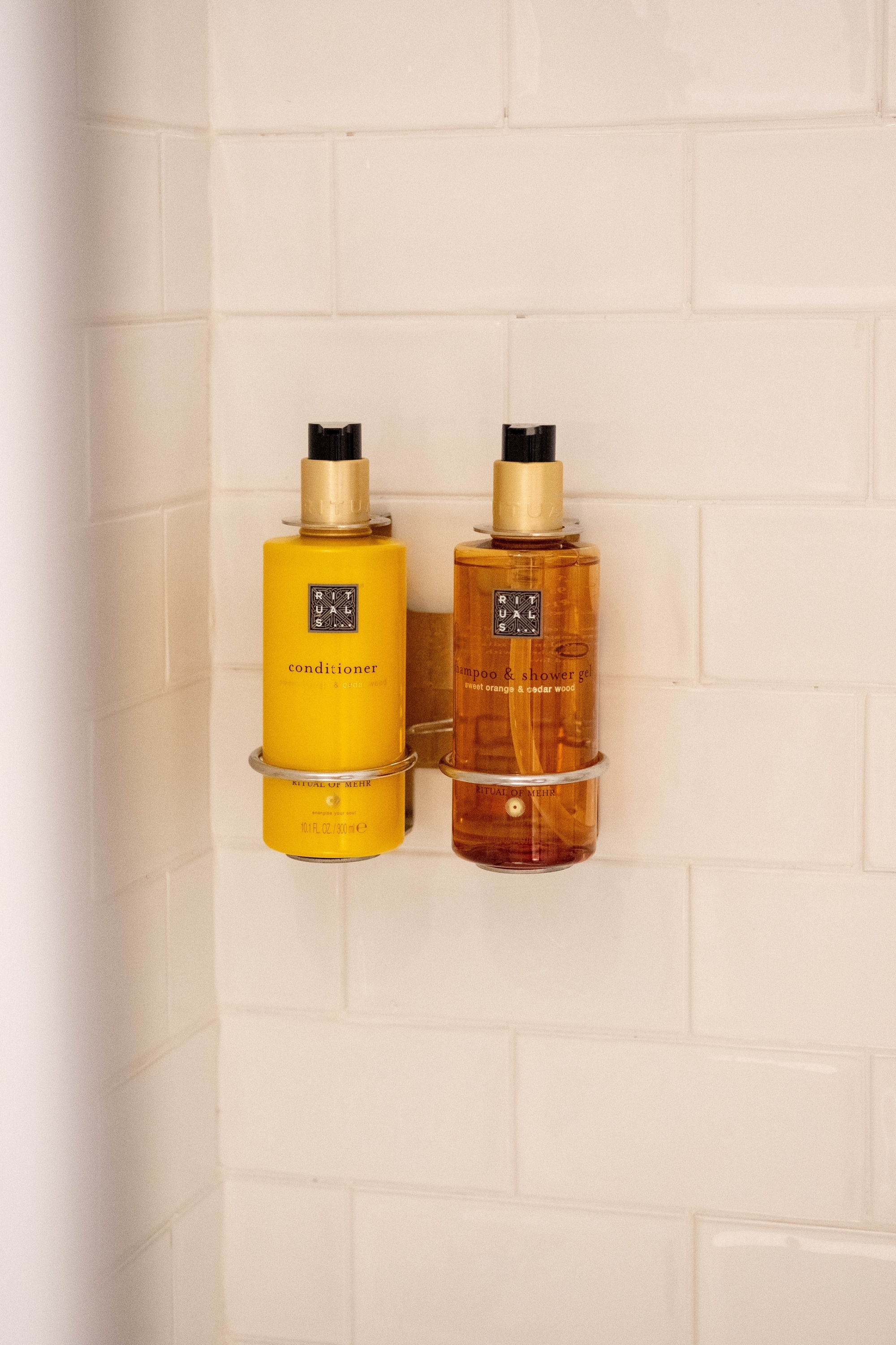 a bottle of conditioner and a bottle of hand soap are hanging on a wall