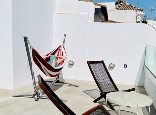 a woman is laying in a hammock on a balcony .