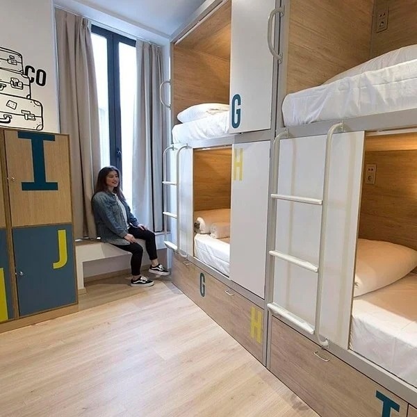 a woman is sitting on a bench in a bunk bed room .