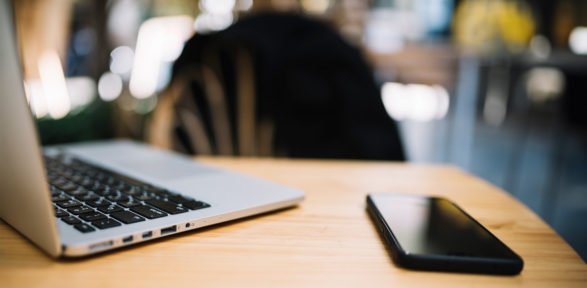 a cell phone sits on a table next to a laptop