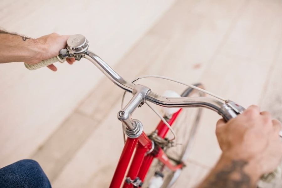 a man is riding a red bicycle with a bell on the handlebars