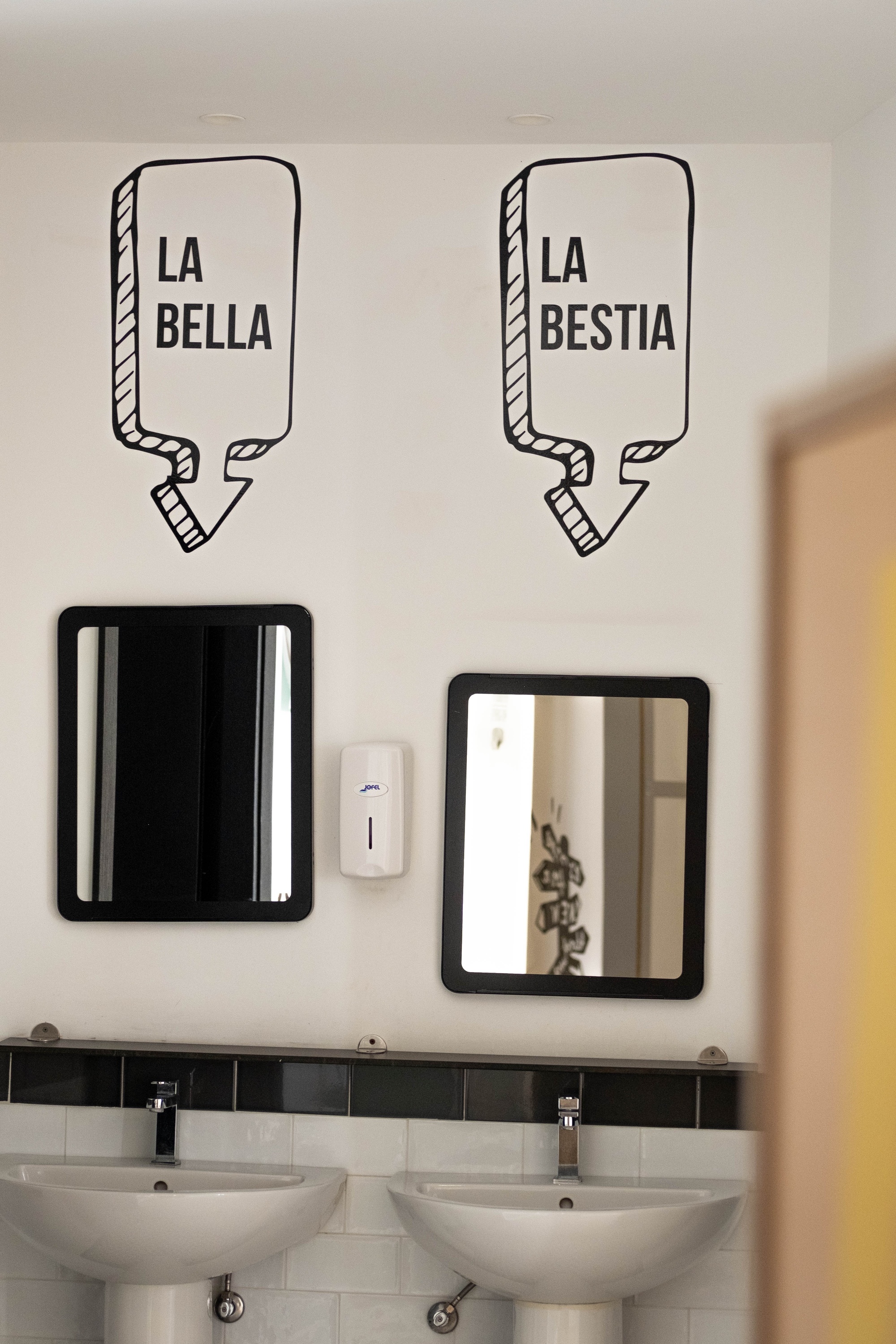 dos lavabos en un baño con etiquetas en la pared que dicen la bella y la bestia