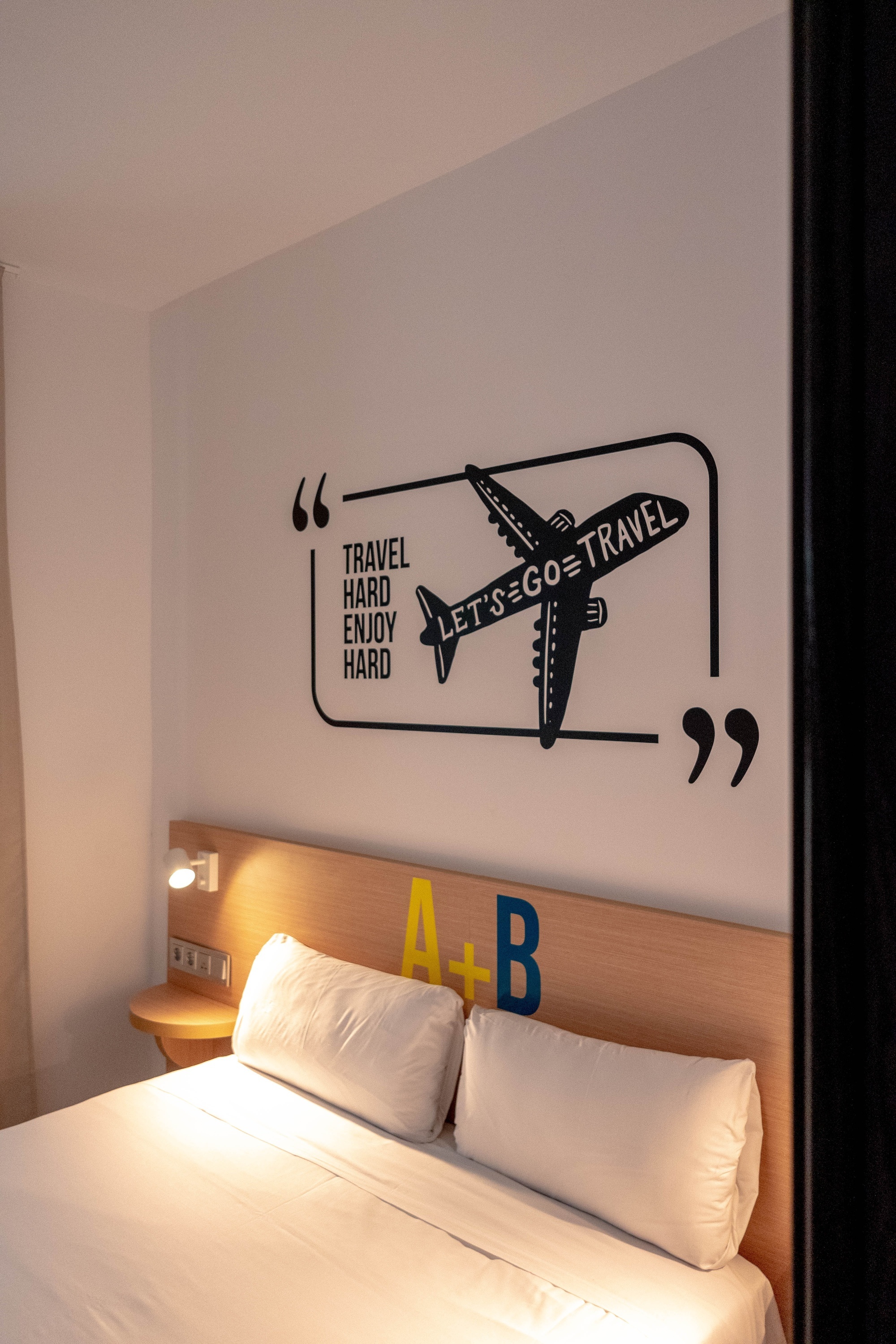 una habitación con una cama y un cartel en la pared que dice " viajar duro y ser feliz duro "
